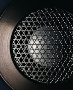 Close up of a speaker with a cross-lattice cover and wide metal rim